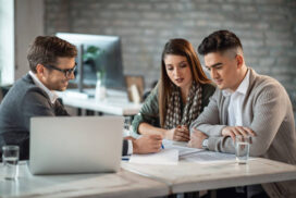 Young couple and bank manager reading financial reports while having a meeting in the office.